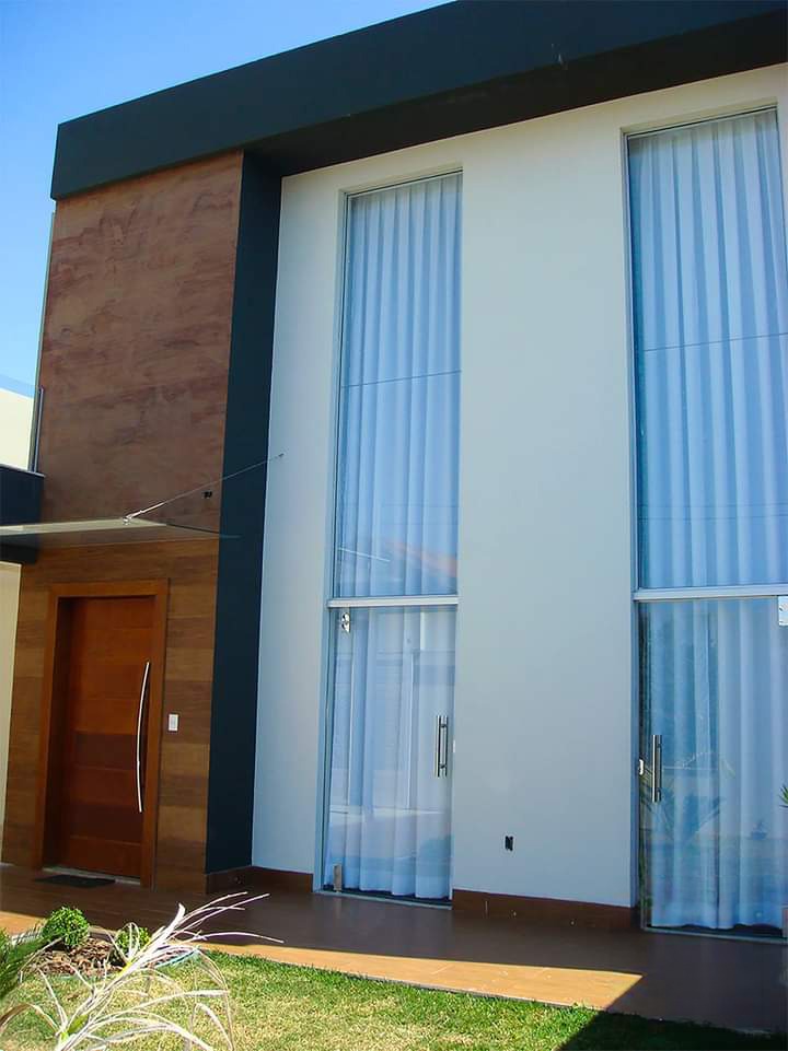 Fachada residencial com portas de vidro e cortinas, projeto de Karla Kétbe Arquitetura
